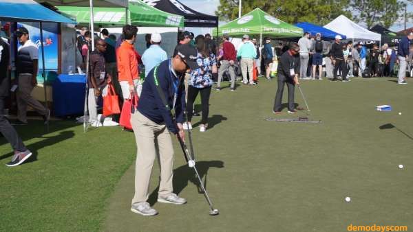 Golfers demo putting gear on the putting green